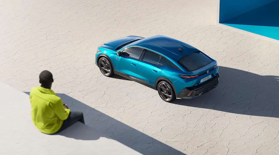 Peugeot 408 en bleu, personne en veste jaune regardant la voiture d'en haut