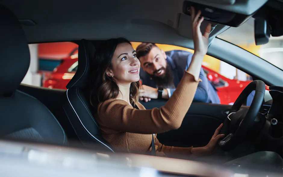 Frau in einem Auto wird von Verkäufer beraten