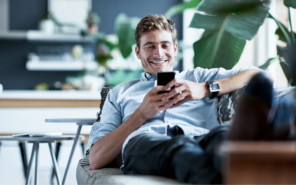 Homme assis sur le canapé et sur son téléphone portable