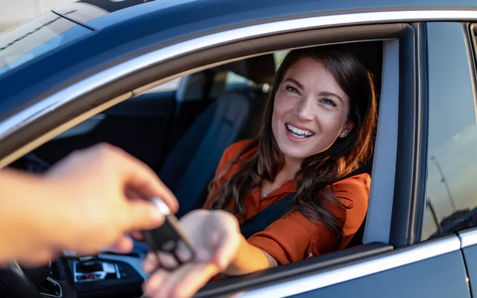 Frau im Auto mit Schlüssel in der Hand