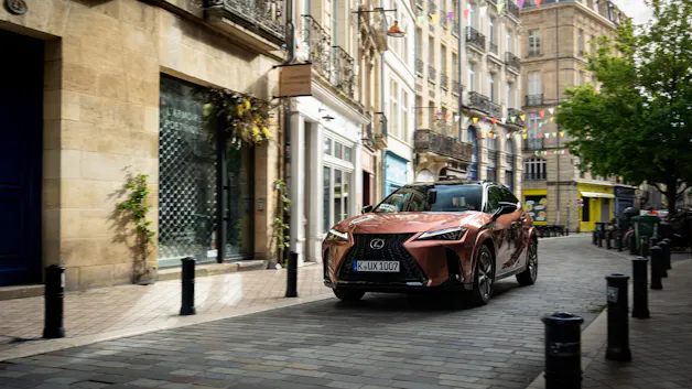La Lexus UX 300h brune se déplace dans une ville