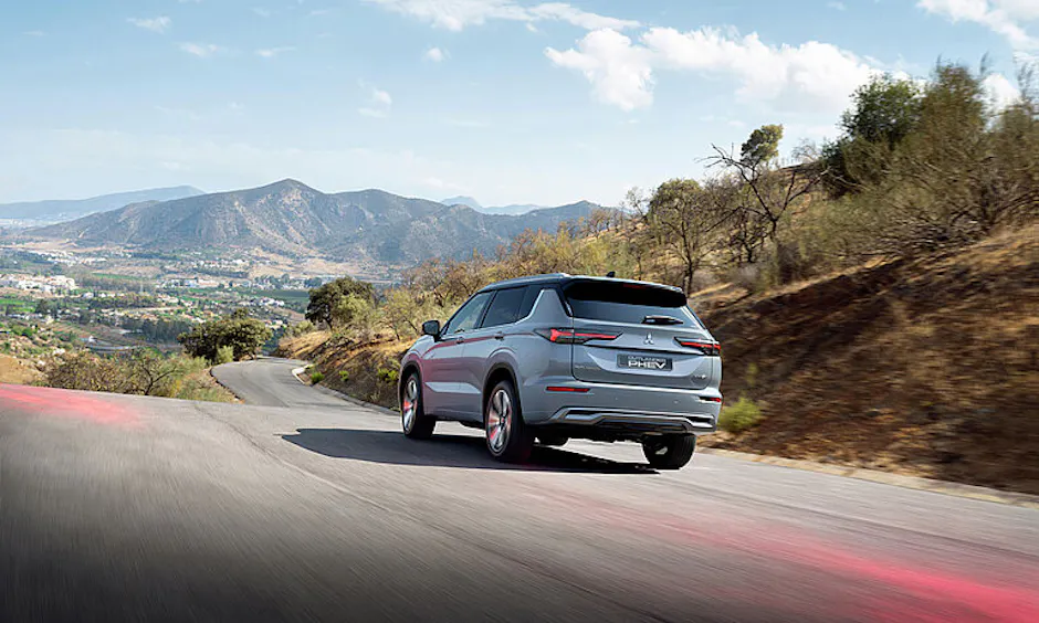 Outlander Plug-in Hybrid alla guida su strada, paesaggio montano sullo sfondo