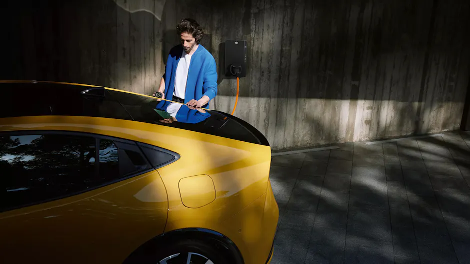 Toyota Prius à la station de recharge, vue de l'arrière avec personne branchant la batterie