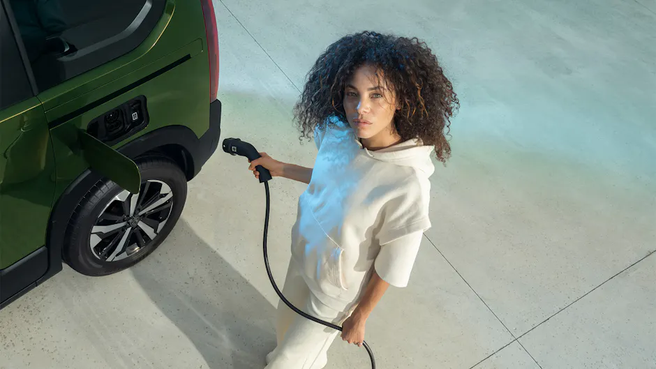 Peugeot E-Rifter en cours de chargement, une dame avec un câble de chargement au premier plan