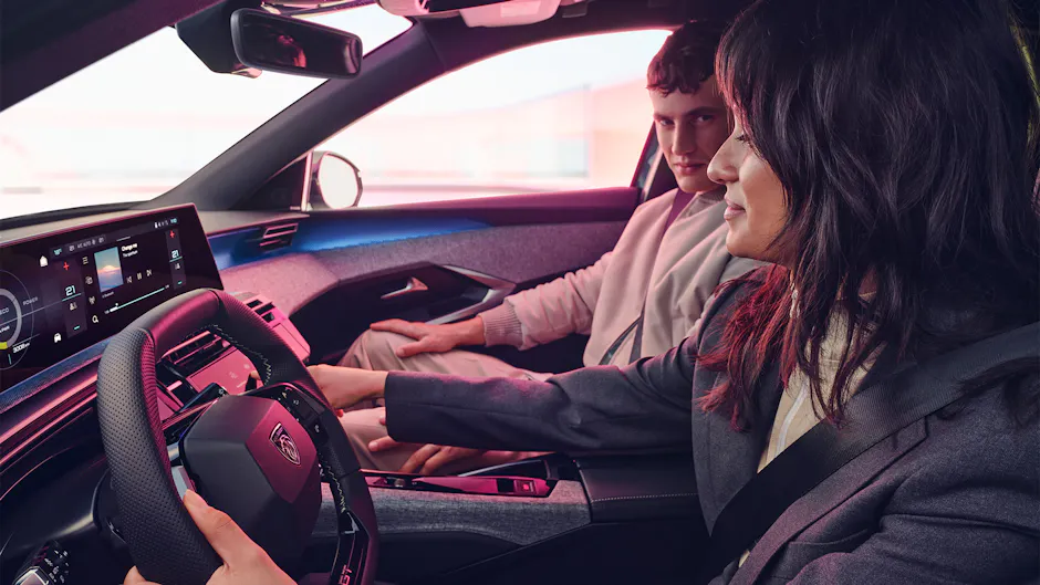 Peugeot E3008 Interieur, eine Frau ist am Lenkrad und benutzt die Mittelkonsole, der Mann auf dem Beifahrersitz schaut zu