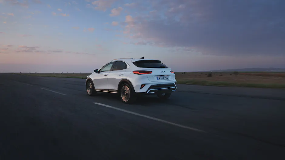 Fahrender Kia XCeed in Weiss in der Dämmerung, von hinten rechts gesehen