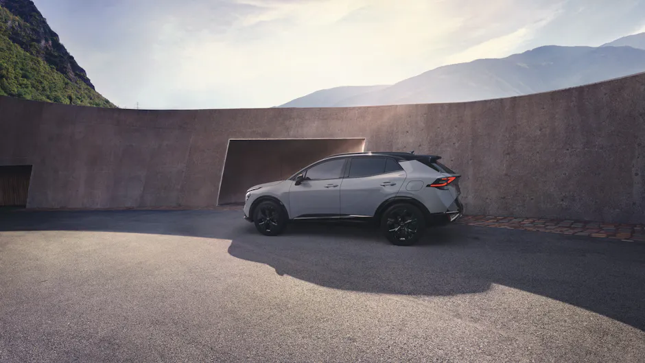 Kia Sportage grigia vista di lato, moderno edificio in cemento sullo sfondo