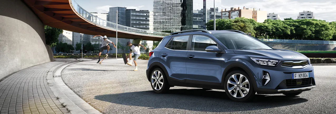 Kia Stonic in der Stadt, Jungen mit Skateboards im Hintergrund