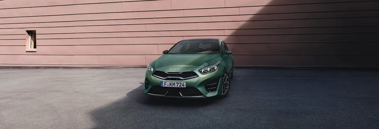 Kia Ceed en vert devant un mur rougeâtre