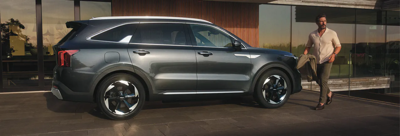 Kia Sorento di colore nero davanti a una casa moderna, un uomo passa davanti a lei