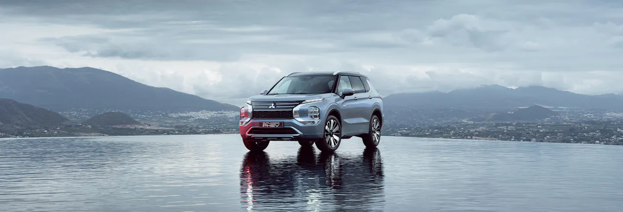 Mitsubishi Outlander PHEV, sur un sol mouillé et une montagne en arrière-plan