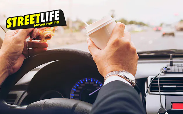 Persona con cibo e tazza di caffè al volante