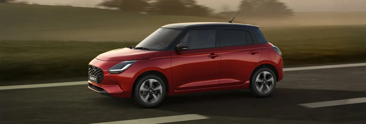 Suzuki Swift che guida di traverso su una strada di campagna al crepuscolo