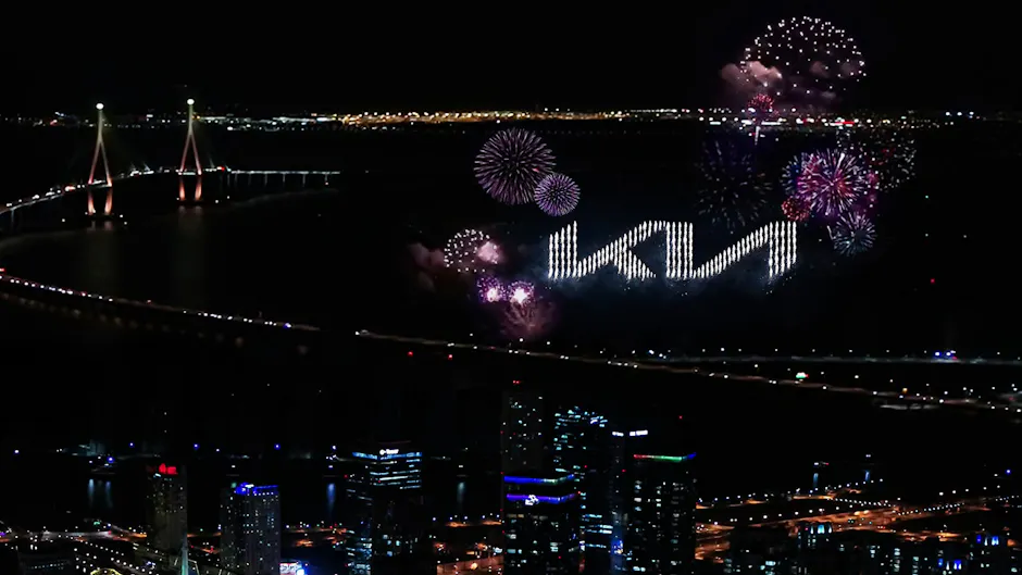 Logo Kia entouré de feux d'artifice, grande ville avec beaucoup d'éclairage tout autour