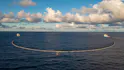 Deux bateaux en pleine mer, tirant un filet pour ramasser les déchets plastiques, le ciel est légèrement nuageux.