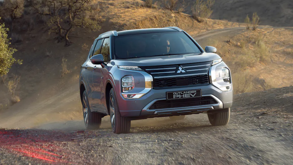 Une Mitsubishi Outlander PHEV argentée roule sur un chemin de gravier