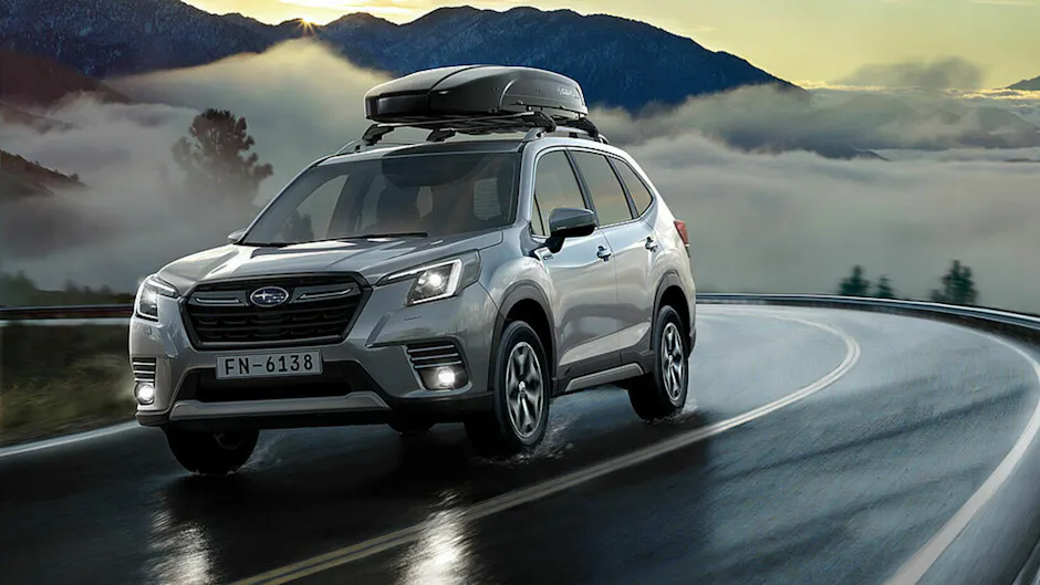 Subaru argento con un box da tetto nero, che percorre una strada di montagna con nebbia sullo sfondo