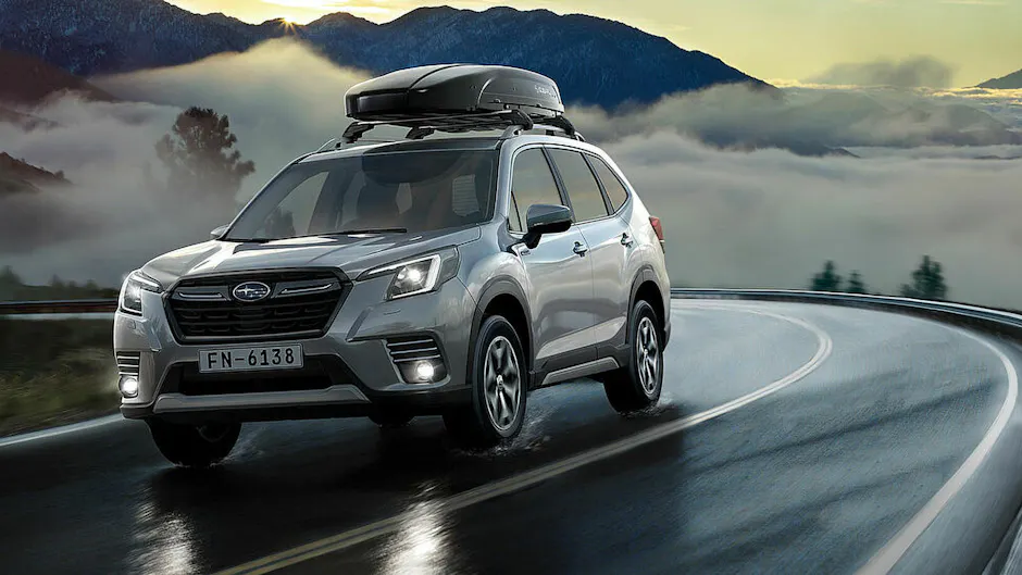 Subaru argento con un box da tetto nero, che percorre una strada di montagna con nebbia sullo sfondo