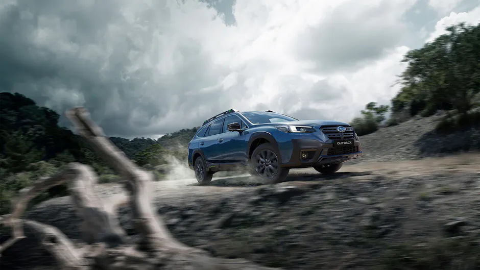 Una Subaru Outback percorre una strada sterrata; sullo sfondo si vedono degli alberi