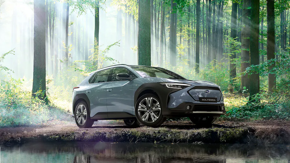Una Subaru in un bosco davanti a uno stagno.