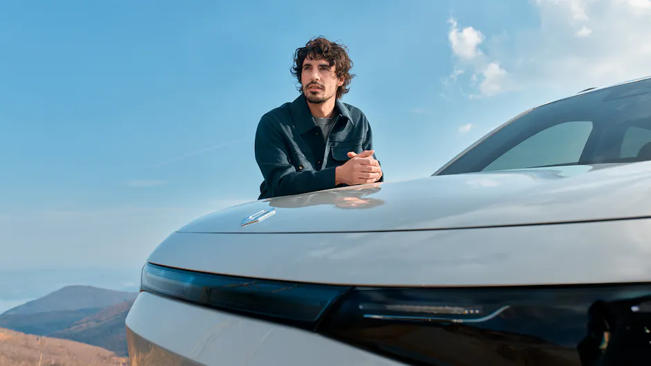 Un uomo si appoggia sul cofano di una Leapmotor, cielo azzurro limpido