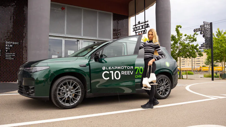 Leapmotor C10 REEV in elegante verde, una donna con i capelli biondi si appoggia alla portiera aperta dell’auto.
