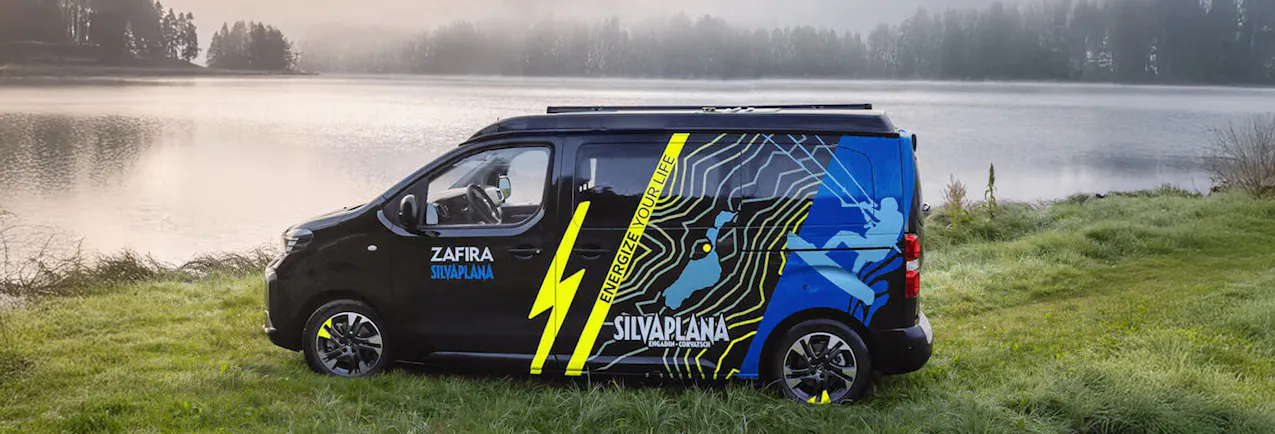 Opel Zafira nero su un prato davanti a un bel lago