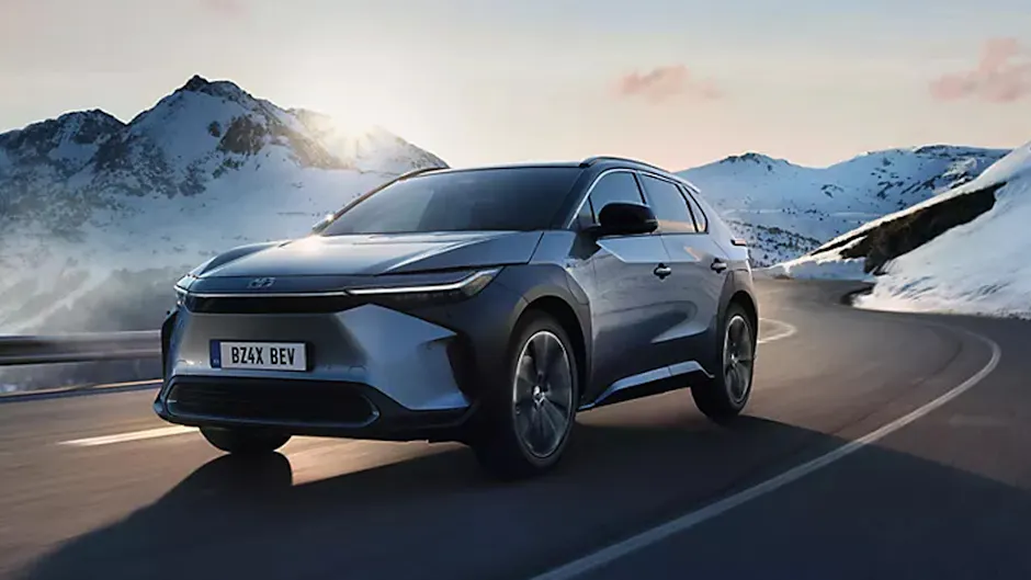 Toyota gris sur une route de montagne, avec des montagnes enneigées en arrière-plan