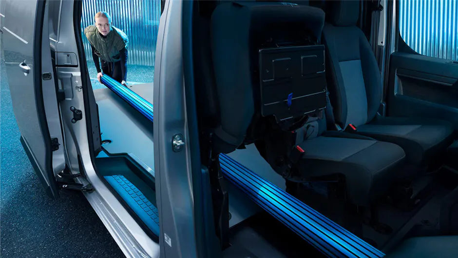 Une femme charge un bus Peugeot avec un poteau bleu