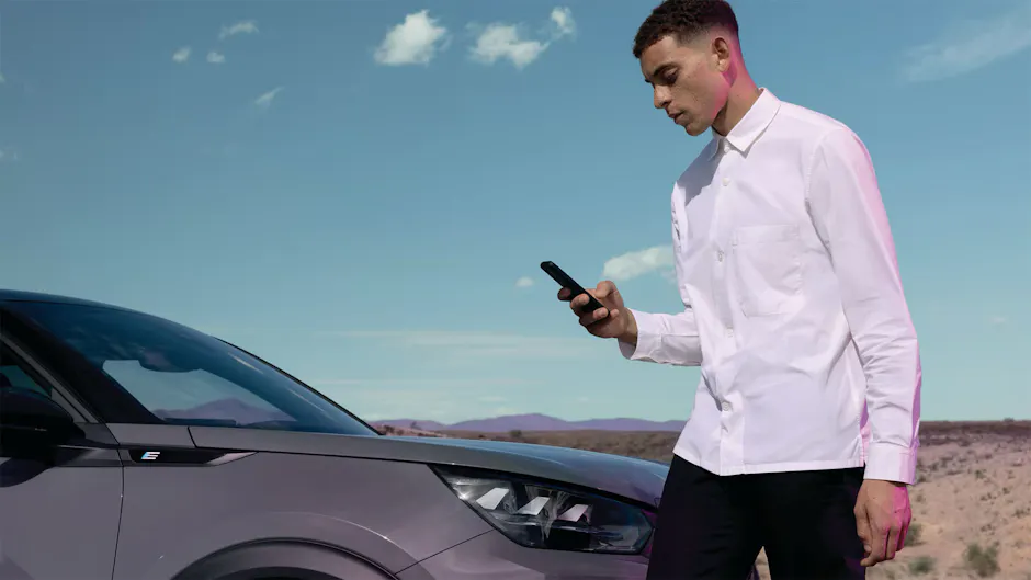 Homme en chemise rose devant une Peugeot