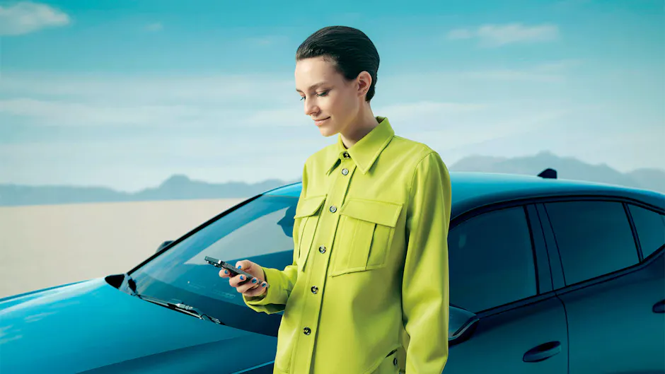 Une femme porte une veste jaune vif devant une Peugeot