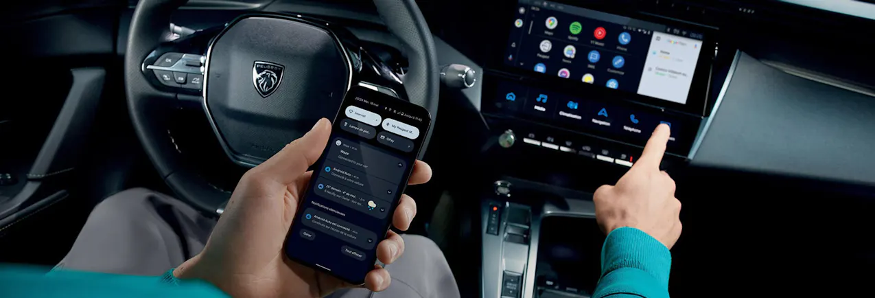 Un homme tenant un téléphone portable montre l'écran d'une Peugeot.