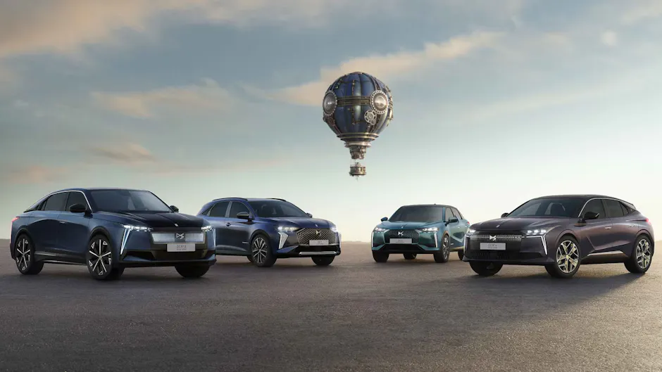 Quattro modelli DS Automobiles visti di fronte; sullo sfondo si vede una mongolfiera, il cielo è leggermente nuvoloso