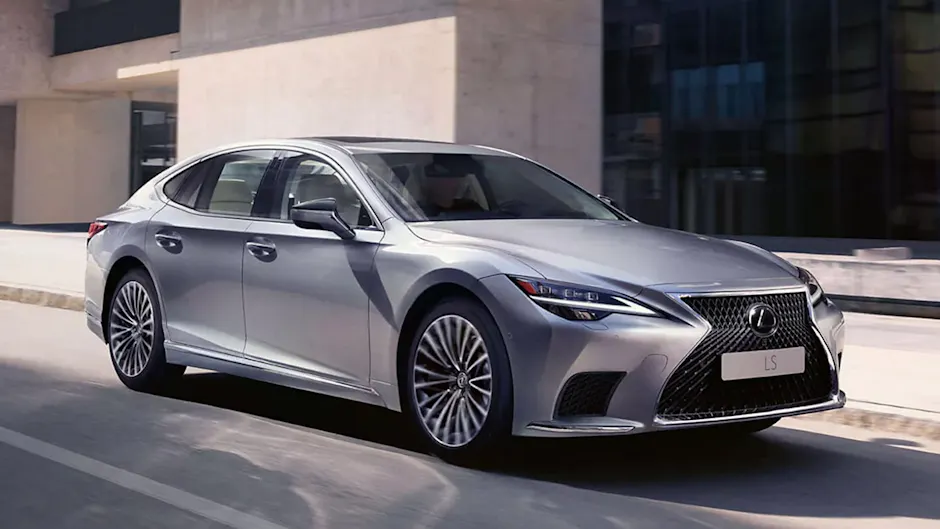 Une Lexus LS argentée vue de profil, avec un immeuble en béton en arrière-plan