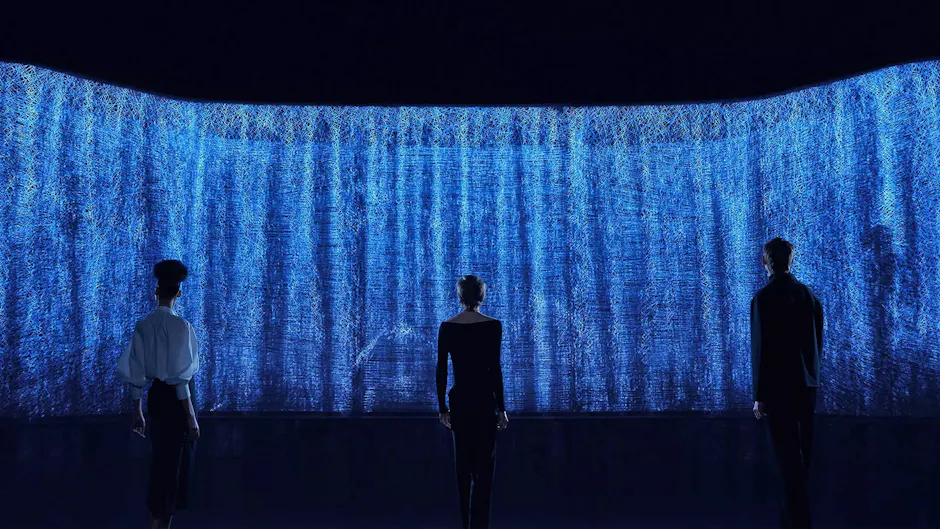 Trois personnes admirent un mur bleu animé