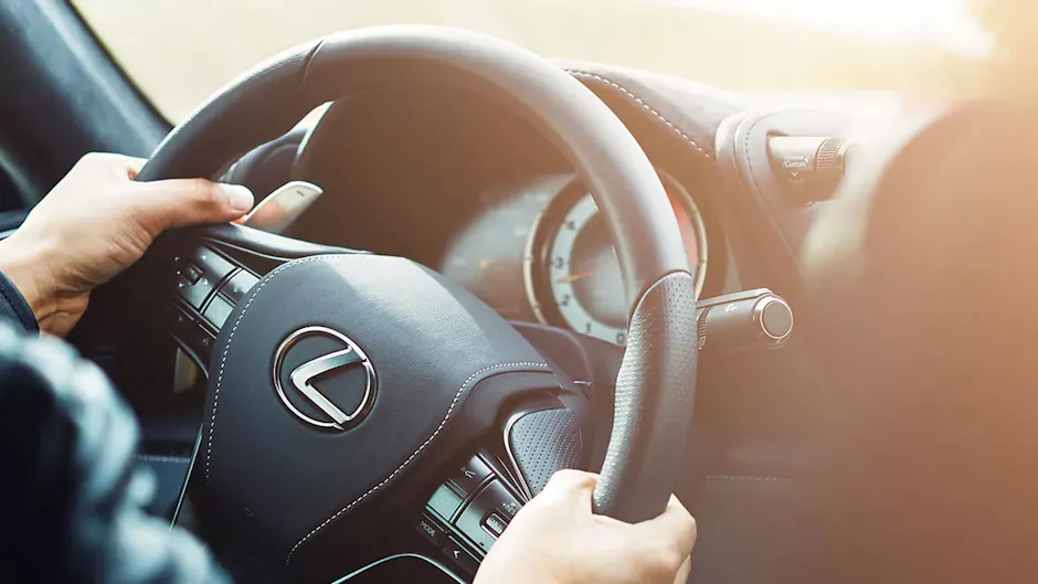 Une personne tient le volant d'une Lexus, dont l'intérieur est noir