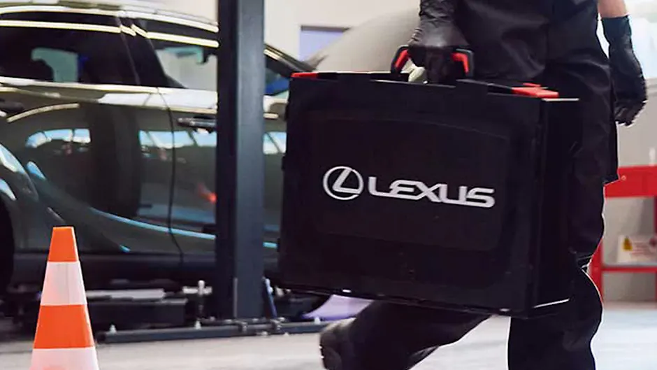 Une personne porte une valise Lexus, avec une voiture en arrière-plan