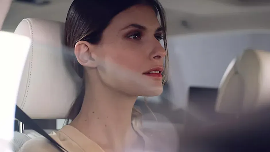 Une femme est assise dans la voiture, l'intérieur est blanc