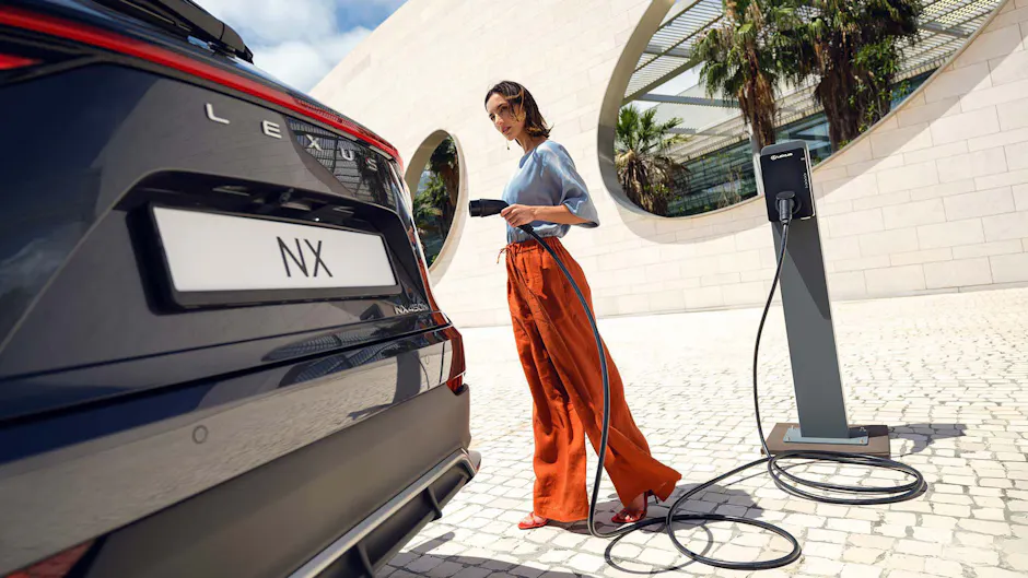 Lexus NX als Plug-in-Hybrid, eine Frau ladet das Auto mit einem Kabel auf