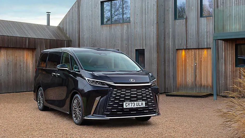 Lexus LM in Schwarz vor einem Haus aus Holz