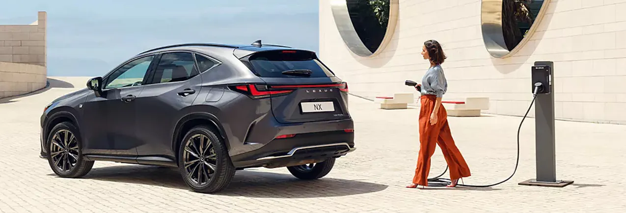 Femme en pantalon rouge charge une Lexus
