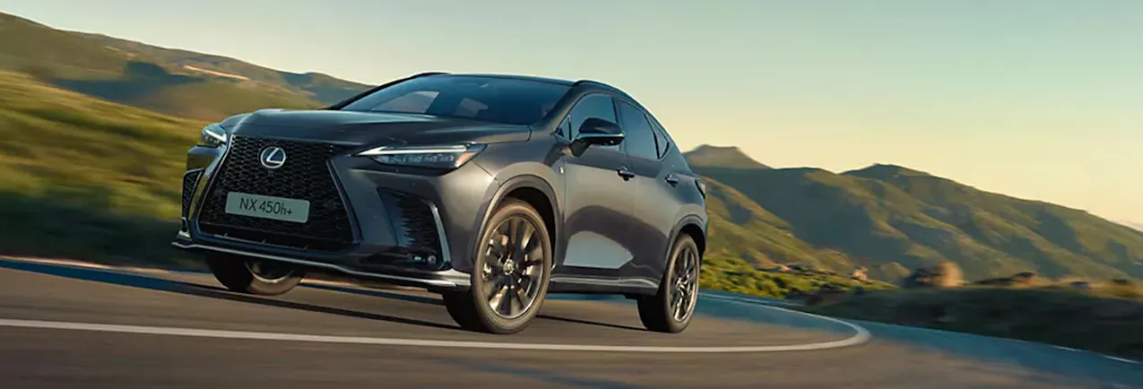 Lexus entièrement électrique sur la route, avec des montagnes verdoyantes en arrière-plan.
