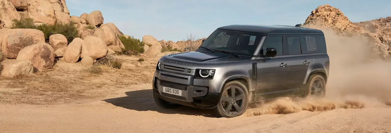 Land Rover Defender in Schwarz, fährt in der Wüste