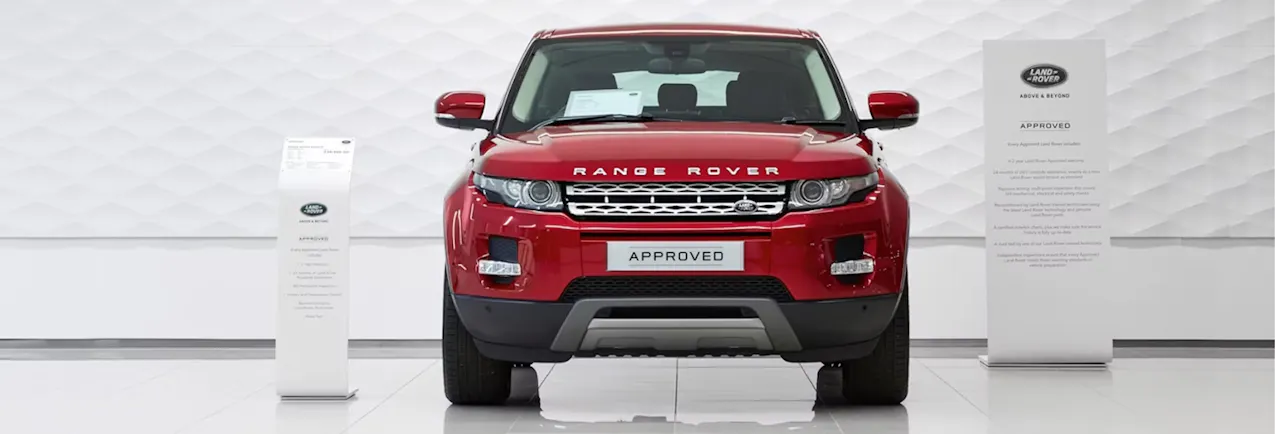 Ein Range Rover in Rot, von Vorne, steht in einem weissen Showroom