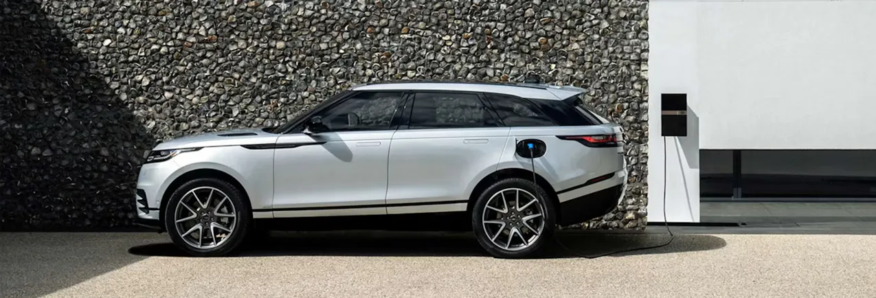 Una Land Rover Velar color argento, in ricarica davanti a un muro di pietra