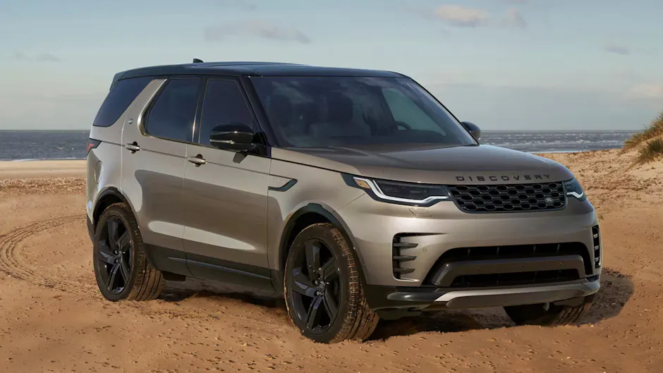 Una Land Rover Discovery grigia è parcheggiata sulla sabbia, con il mare sullo sfondo