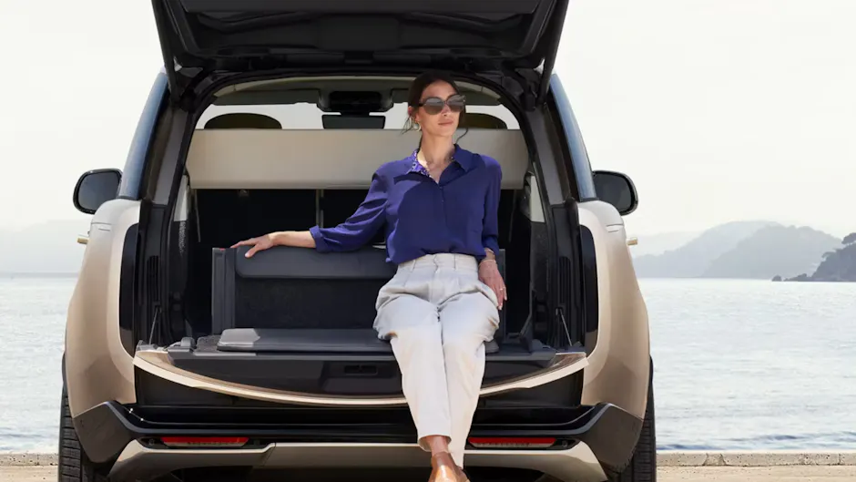 Una donna è seduta nel bagagliaio di una Range Rover color oro a Batumi, con il mare sullo sfondo