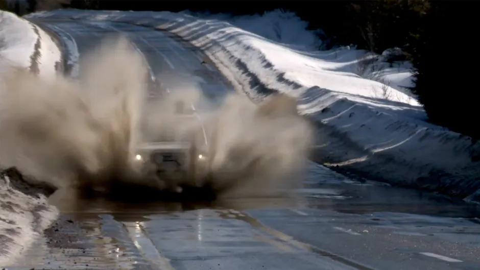 Land Rover fährt durch eine Pfütze und spritzt Wasser