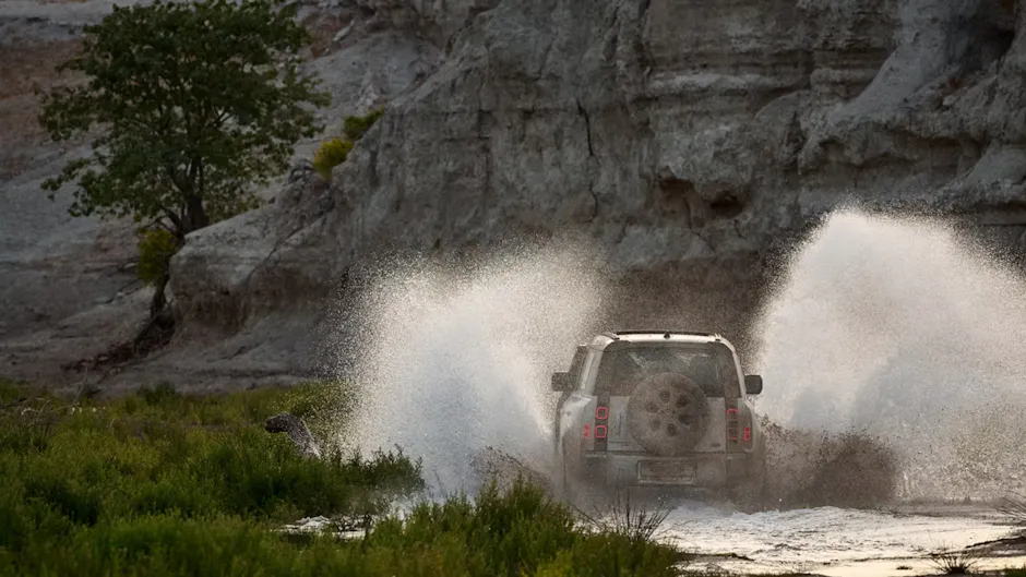 Una Land Rover bianca attraversa rapidamente l'acqua