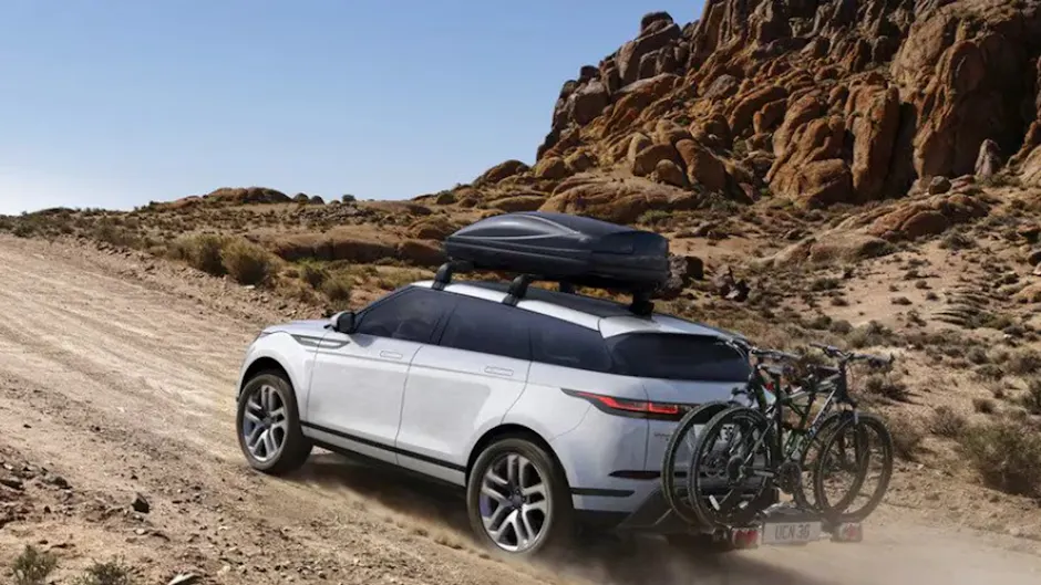 Range Rover bianca, guida nel deserto, con un portabici e un box da tetto nero